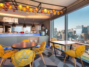una cucina con tavoli e sedie e una vista sulla città di ibis Styles Ambassador Seoul Myeong-dong a Seul