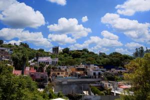 una ciudad con edificios en una colina con nubes en el cielo en Villa 19 habitación #2 en Guanajuato