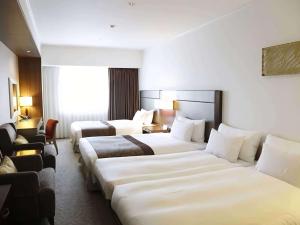 札幌市にあるイビス スタイルズ 札幌のベッド3台と椅子が備わるホテルルームです。