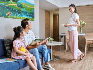 una mujer hablando con una familia en una sala de estar en Novotel Hanoi Thai Ha, en Hanói