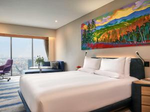 1 cama blanca grande en una habitación de hotel con una gran pintura en Novotel Hanoi Thai Ha, en Hanói