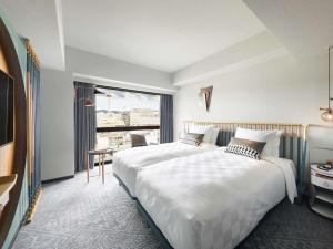 a hotel room with two beds and a large window at Mercure Kyoto Station in Kyoto