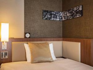 a bedroom with a bed with a clock on the wall at ibis Styles Tokyo Ginza in Tokyo