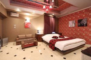 - une chambre avec un lit, une chaise et un canapé dans l'établissement HOTEL K-WAVE R (Adult Only), à Koshigaya
