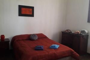 sypialnia z czerwonym łóżkiem i 2 ręcznikami w obiekcie Casa Quinta w mieście Colonia Caroya