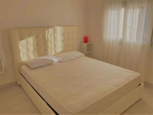a white bed in a white room with a window at Apartment in Albarella 42379 in Palazzo Vianello
