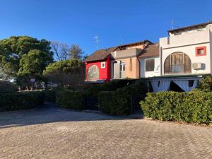 a house with a red door on a driveway at Apartment in Albarella 42379 in Palazzo Vianello +4 photos