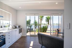 a kitchen with white cabinets and a view of the ocean at Waterfront Retreat - Westport Self-Contained Unit in Westport