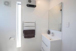 ein weißes Badezimmer mit einem Waschbecken und einem Spiegel in der Unterkunft Waterfront Retreat - Westport Self-Contained Unit in Westport