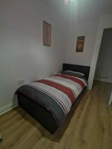 a bed in a room with white walls and wooden floors at Langley Haven - 3 BR House in Kent
