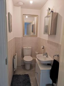 a bathroom with a toilet and a sink and a mirror at Langley Haven - 3 BR House in Kent