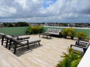 a patio with benches and a couch on a roof at MODERNO DEPARTAMENTO EN EL CENTRO in Tulum
