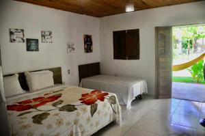 a bedroom with two beds and a door to a yard at Pousada e Restaurante Encanto das Águas in São Miguel dos Milagres