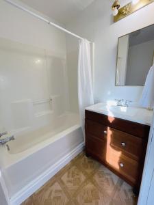 een badkamer met een wastafel, een bad en een spiegel bij Comfy Guesthouse in Yelm in Yelm
