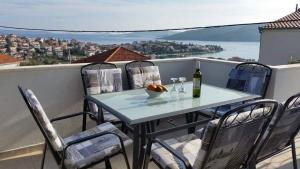 a table and chairs on a balcony with a bottle of wine at Apartments with parking space Seget Vranjica, Trogir - 16661 in Donji Seget