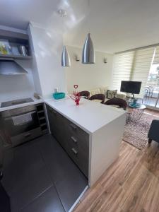 cocina con encimera blanca y sala de estar en Departamento en Bosques de Montemar, en Concón