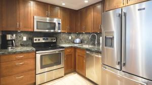 una cocina con armarios de madera y electrodomésticos de acero inoxidable en Maui Westside Presents: Whaler 420 - Best location in Kaanapali beach, en Lahaina