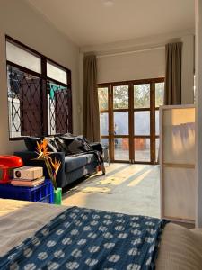 a bedroom with a bed and a couch and windows at Cozy villa in Chiangmai old town in Chiang Mai
