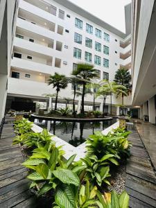 a large building with palm trees in a courtyard at Kuching BDC Saradise Rex Apartment in Kuching