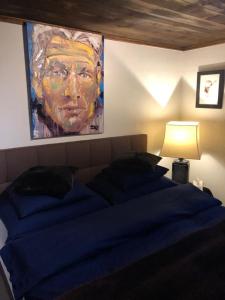 a bedroom with a blue bed with a painting on the wall at Chalet OG Harfe in Davos