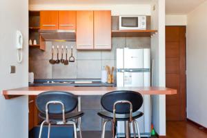 cocina con 2 taburetes y nevera en Apartment located in midtown en Santiago