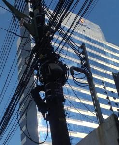 un poste con líneas de energía frente a un edificio alto en APART HOTEL SENSE II - Localizado em Hotel, en Manaus