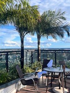 a patio with a table and chairs and palm trees at APART HOTEL SENSE II - Localizado em Hotel in Manaus