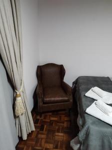 a chair sitting next to a bed in a room at Château Capivari - Campos do Jordão in Campos do Jordão