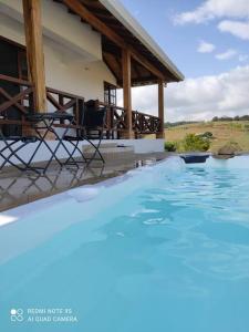 una piscina frente a una casa con sillas en Hermosa casa campestre con hidropiscina en Los Santos