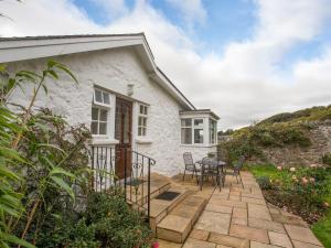 a white cottage with a table and chairs on a patio at Bwthyn at Brynhyfryd in Pwllheli