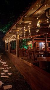 bar z drewnianymi stołami, krzesłami i światłami w obiekcie Pousada Chalés do Rancho Canastra w mieście Vargem Bonita