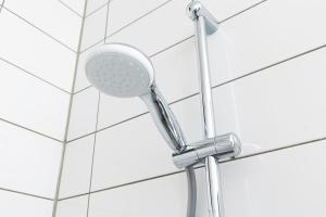 a shower head on a white tiled wall at Luxurious Loft apt w-View walk city center New Delft Family XL in Delft