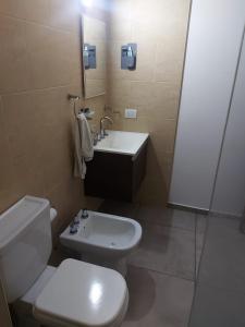 y baño con aseo blanco y lavamanos. en Departamento con Cochera Privada Playa Necochea en Necochea