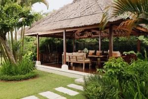 a pavilion with a table and chairs in a garden at Villa Uma Nina by Nakula in Jimbaran