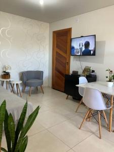 - un salon avec une télévision, une table et des chaises dans l'établissement Ap Garden - Cachoeira do Bom Jesus - 400m da praia, à Florianópolis