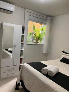 1 dormitorio con cama, espejo y ventana en Ap Garden - Cachoeira do Bom Jesus - 400m da praia en Florianópolis