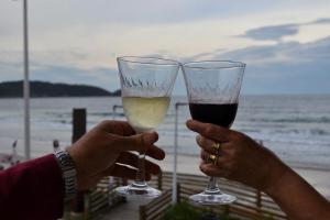 dos personas sosteniendo copas de vino cerca de la playa en Bombinhas à beira-mar, en Bombinhas