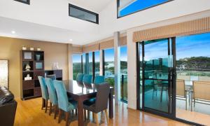 a dining room with a table and chairs and glass windows at Belbourie in Queenscliff