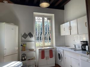 una cucina con armadi bianchi, lavandino e finestra di Gîte Trévol, 5 pièces, 8 personnes - FR-1-489-223 a Trévol