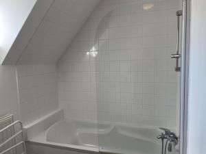 y baño con bañera y azulejos blancos. en Gîte Trévol, 5 pièces, 8 personnes - FR-1-489-223 en Trévol