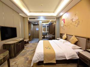 a bedroom with a large bed and a flat screen tv at Zhangye Kerry Hotel in Zhangye