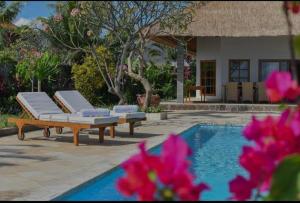 - une piscine avec 2 chaises longues à côté d'une maison dans l'établissement Beachfront Private VILLA & POOL, à Banjar