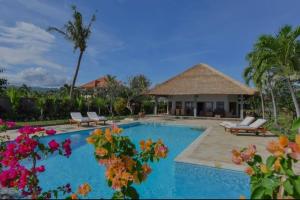 - une piscine entourée de chaises et de fleurs dans l'établissement Beachfront Private VILLA & POOL, à Banjar
