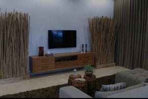una sala de estar con TV en un centro de entretenimiento de madera en Beachfront Private VILLA & POOL, en Banjar