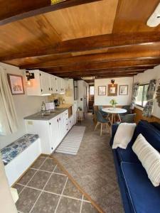 Una sala de estar con un sofá azul y una cocina. en Driftwood Cozy Houseboat on the Water for 2, en Savanna