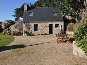 ein kleines Steinhaus mit einem Tisch und einer Bank in der Unterkunft Maison Trégastel, 3 pièces, 4 personnes - FR-1-368-27 in Trégastel