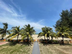 een weg die leidt naar een strand met palmbomen bij DSH Batu Burok Beach Resort in Kuala Terengganu