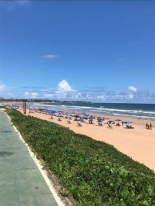 a beach with chairs and umbrellas and the ocean at FLAT ENCANTADOR A UM PASSO DA PRAIA in Salvador