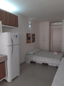 a small kitchen with two beds and a refrigerator at FLAT ENCANTADOR A UM PASSO DA PRAIA in Salvador