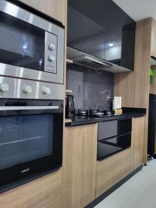 a kitchen with a stove and a microwave at La Foret 2 dormitorios in Santa Cruz de la Sierra